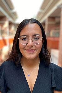 Woman with olive and skin shoulder length black hair wearing a black shirt and glasses